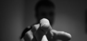 Detalhe de um dedo indicador em riste direcionado à câmera. Foto preta e branca.